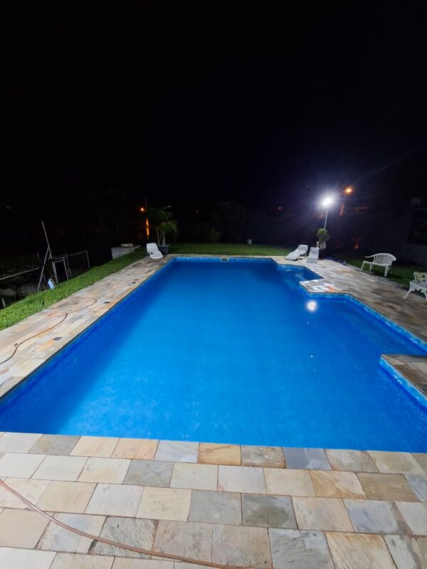A mesma piscina com água azul e transparente, à noite