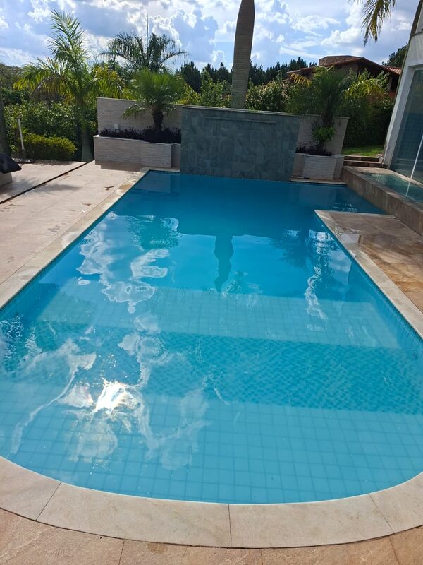 Piscina com cascata e água azul clara ao sol